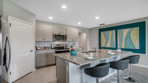 Kitchen with island seating, granite counters, spacious pantry and stainless steel appliances.