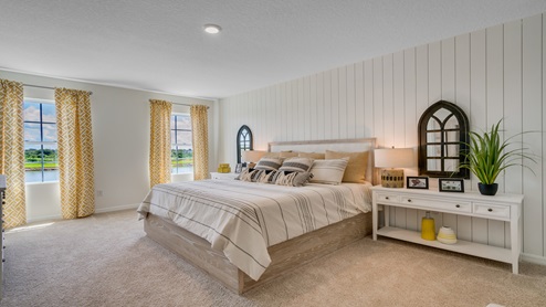 Spacious primary bedroom with king size bed, carpet flooring, and natural lighting.