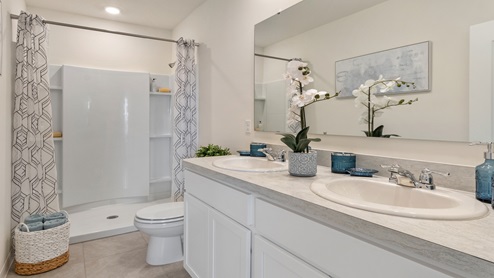 Single vanity bathroom with granite countertop, large wall mirror, toilet and walk-in shower.