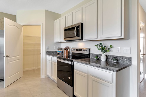 Kitchen with tall cabinetry, appliances, and spacious walk-in pantry
