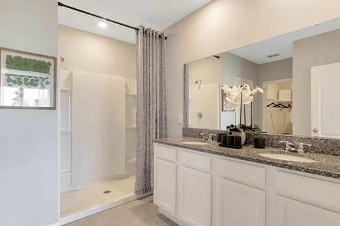 Modern bathroom with double vanity, large wall mirror, cabinets and granite countertops.